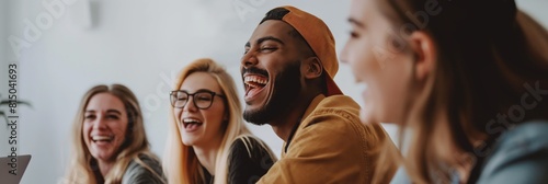 A diverse group of young adults share a humorous moment, laughing together in a modern office or co-working space photo