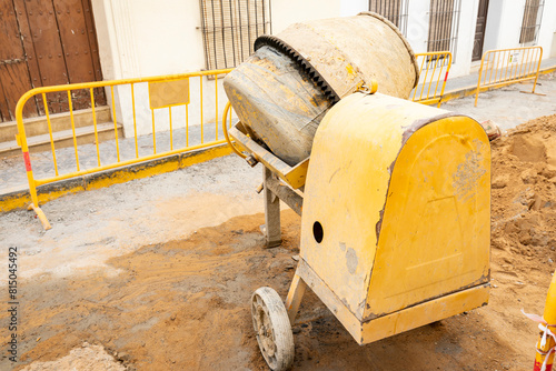 reconstruction work on a city street - a yellow concrete mixer on a construction site
