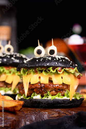 Monster Burger. Black bun  juicy beef cutlet  lettuce  onion  tomato and cheese in the shape of teeth  mozzarella eyes with olives. Definitely a pick-me-up and a perfect Halloween party appetizer.