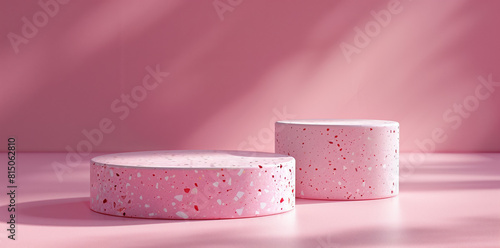 two pink terrazzo cylinder podiums in different sizes, on soft pink background, minimalism