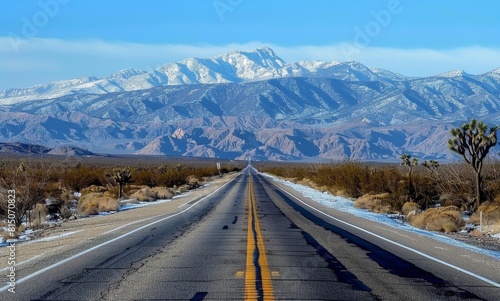 an empty highway with mountains in the background, the road leads to horizon, the sky is clear and blue