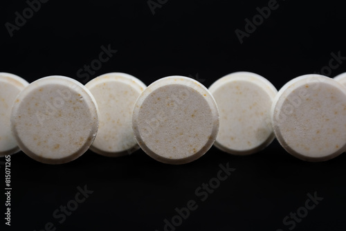 White pills on a black background. Focus on foreground, shallow depth of field.