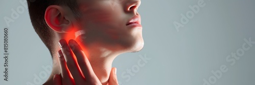 A close-up image of a man seemingly suffering from throat pain with red light highlighting the painful area photo