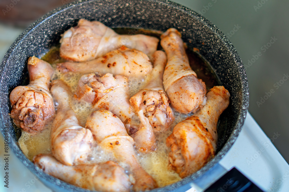 Sizzling chicken legs browning in a skillet Sizzling chicken legs browning in a skillet