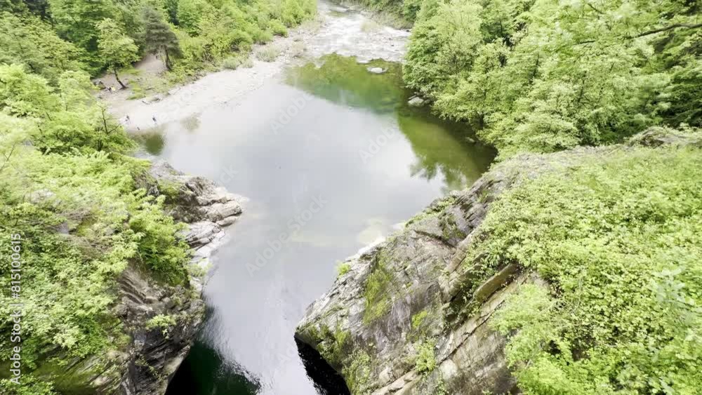 Expansive view of a tranquil river pool surrounded by lush green forests in Orrido di Sant'Anna, Traffiume, Cannobio, under a cloudy sky, Piemont, Italy Expansive view of a tranquil river pool surrounded by lush green forests in Orrido di Sant'Anna, Traffiume, Cannobio, under a cloudy sky, Piemont, Italy