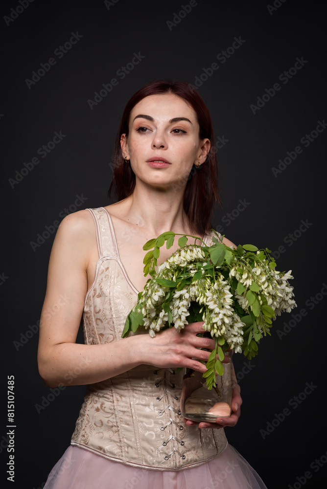 A captivating woman poses in a photo studio with an acacia branch. A captivating woman poses in a photo studio with an acacia branch.