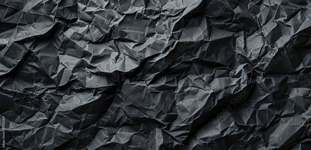A closeup of crumpled black paper texture, with dark gray and matte tones. A closeup of crumpled black paper texture, with dark gray and matte tones.