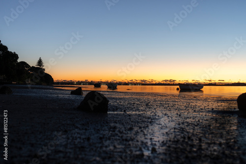 TAuranga harbour sunrise backlights intertidal area and dinghy