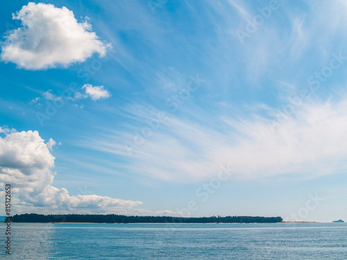 Two cloud formations over sea and low island background.