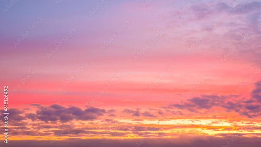 Fototapeta premium A beautiful sunset with pink and orange clouds in the sky. The sky is filled with clouds and the sun is setting, creating a warm and peaceful atmosphere