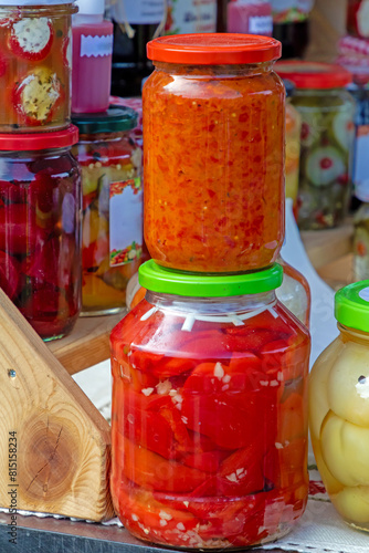 Organic home made perserved pickled vegetables in glass jars sold outside on a market stall photo