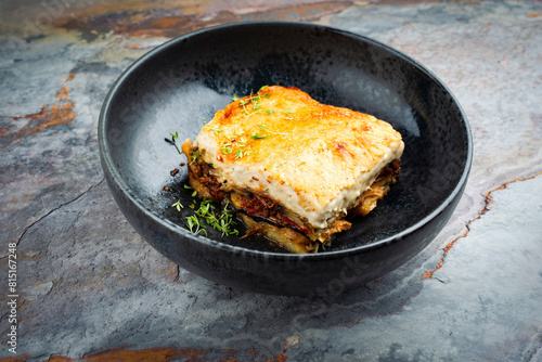 Traditional Greek moussaka with beef mince, eggplant and bechamel sauce served as close-up in a Nordic design Bowl on a stone board © HLPhoto