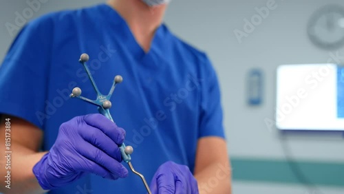 Unrecognized doctor in blue uniform holding a navigated tool equipped with reference frame for neurosurgical operation. Medic attaches the instrument to the head of the patient. Close up. photo