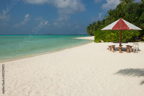 Tropical beach with palm trees, umbrella and table for relaxing moments