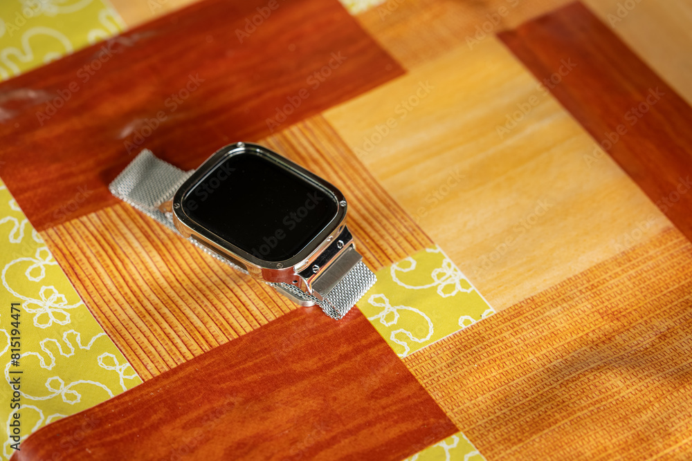 Square smart watch with metal strap lying on the table. Square smart watch with metal strap lying on the table.