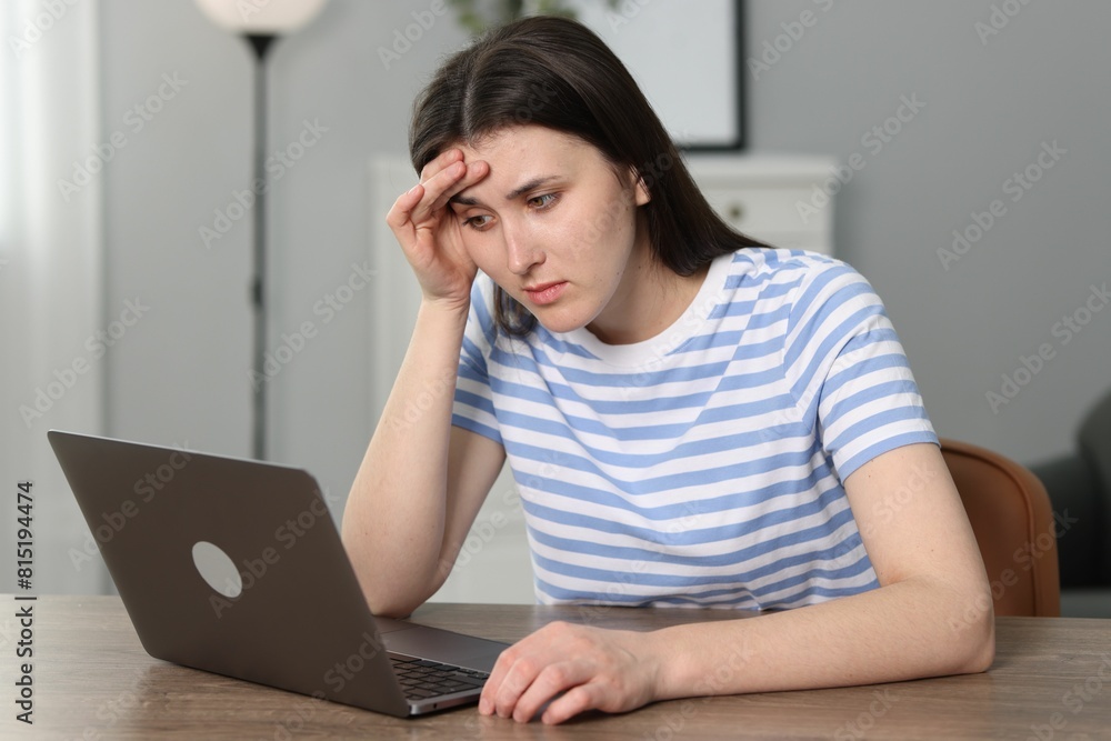 Overwhelmed woman sitting with laptop at table indoors Overwhelmed woman sitting with laptop at table indoors