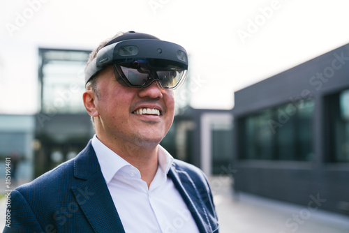 A businessman in a suit smiling while wearing virtual reality glasses, standing in front of a modern office building
