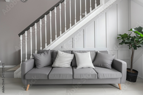 Cute grey sofa in room with staircase. Scandinavian home interior design of modern living room.