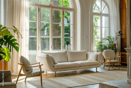 Beige sofa and armchair in room with arched windows. Luxury mid-century style home interior design of modern living room.