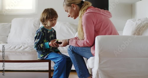 A mother attentively uses a pulse oximeter on her young sons finger to measure his oxygen saturation while they sit together indoors. photo
