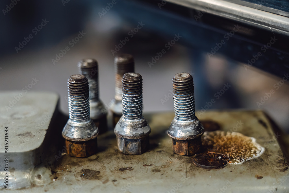 Unscrewed rusty wheel bolts in a car service center Unscrewed rusty wheel bolts in a car service center