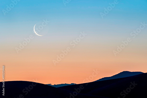 Sunset in the mountains with a crescent moon