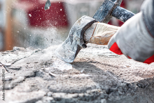 Worker using a sledgehammer to cut a stone with cement. Construction site worker