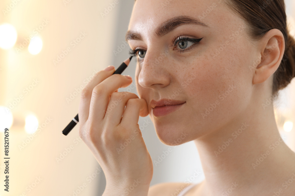 Fototapeta premium Makeup product. Woman applying black eyeliner indoors, closeup