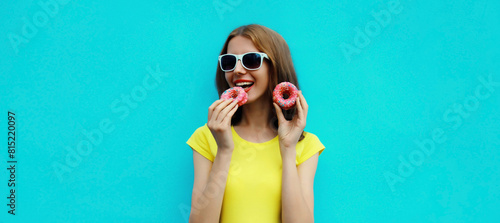 Portrait happy cheerful smiling young woman with sweet donut having fun on blue background