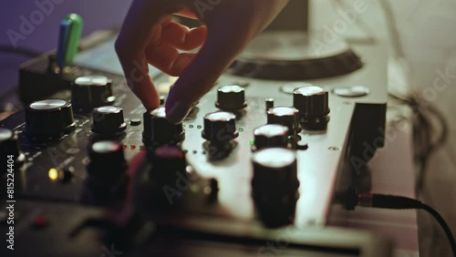 DJ hand tweaking knobs on mixer mixing music in clubbing scene closeup.  photo