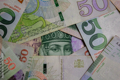 Top view. Photo closeup. Green paper banknotes of Georgia. 50 GEL. Georgian lari. Cash money. Portrait of Queen Tamara. Women's rights. Female eyes. Concept of tax, debt, currency exchange, loan. Bill