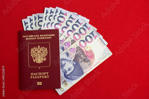 Top view. 100 GEL. One hundred lari. Photo with biometric Russian passport and paper cash Georgian banknote on red textile background. Money to pay for purchases. Concept of tourism, travel. Bill