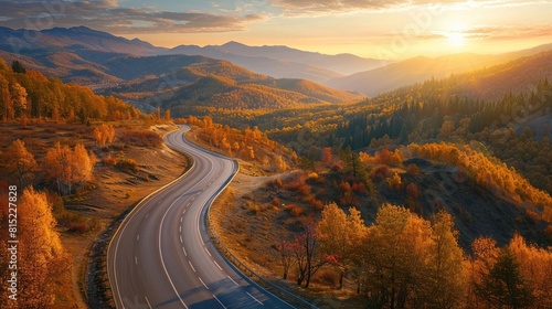 Aerial view of mountain road in orange forest at sunset in autumn. Beautiful landscape with empty highway, hills, pine trees, golden sunlight in fall. Panoramic view of a 