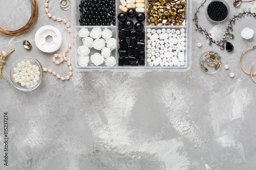 Tools and beads for making handmade jewelry on concrete background, top view