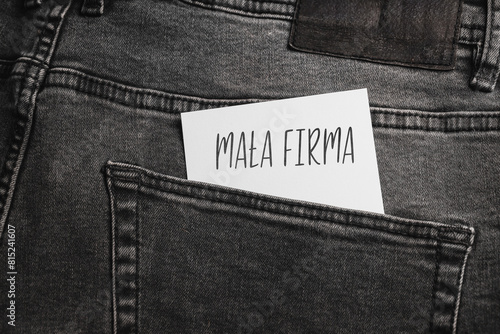  White card with a handwritten inscription "Mała Firma", inserted into the pocket of gray pants jeasnow (selective focus), translation: small business