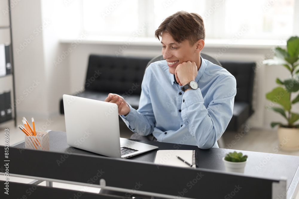 Man using video chat during webinar at table in office Man using video chat during webinar at table in office