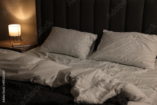 Soft bed and bedside table with nightlight indoors
