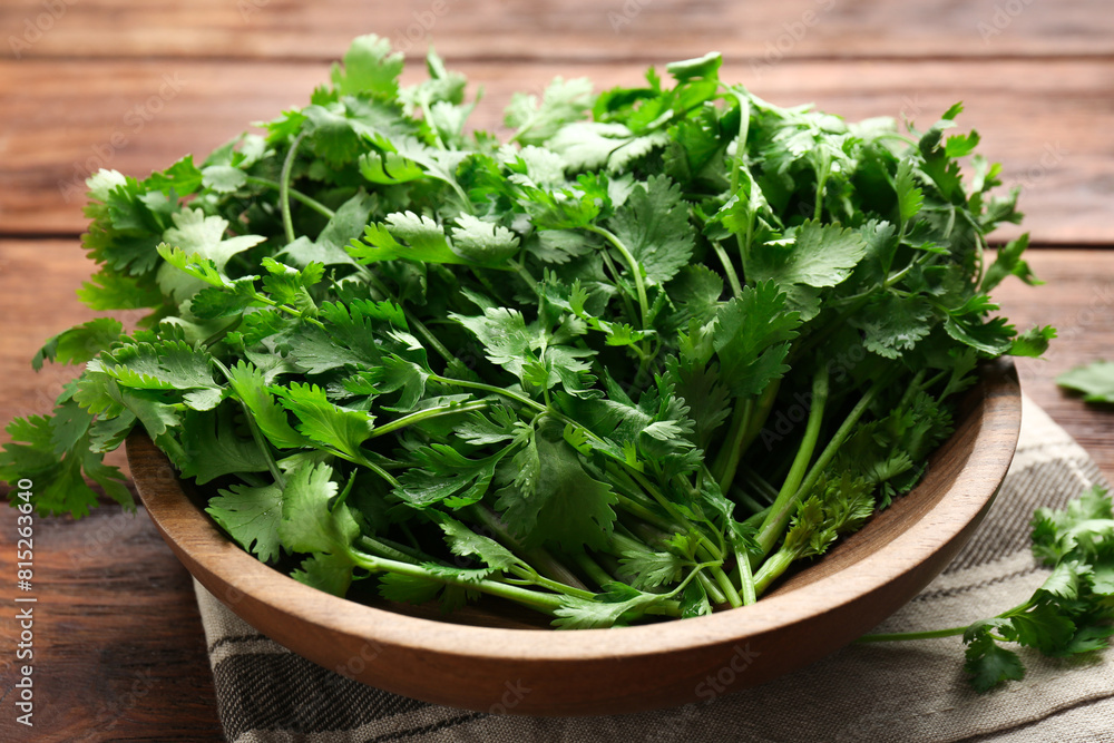 Fresh coriander in bowl on wooden table, closeup Fresh coriander in bowl on wooden table, closeup