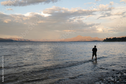 Sports and recreation. View of a man fishing from the rocky shore in Nahuel Huapi lake at sunset. photo