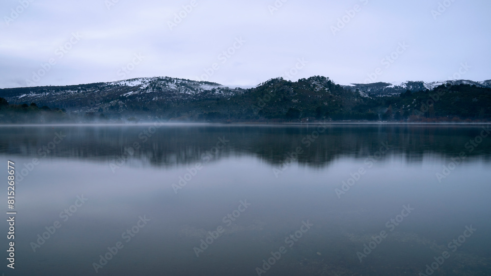 Long exposure view of the serene lake, forest and mountains at sunrise. Beautiful landscape reflection in the water surface. 