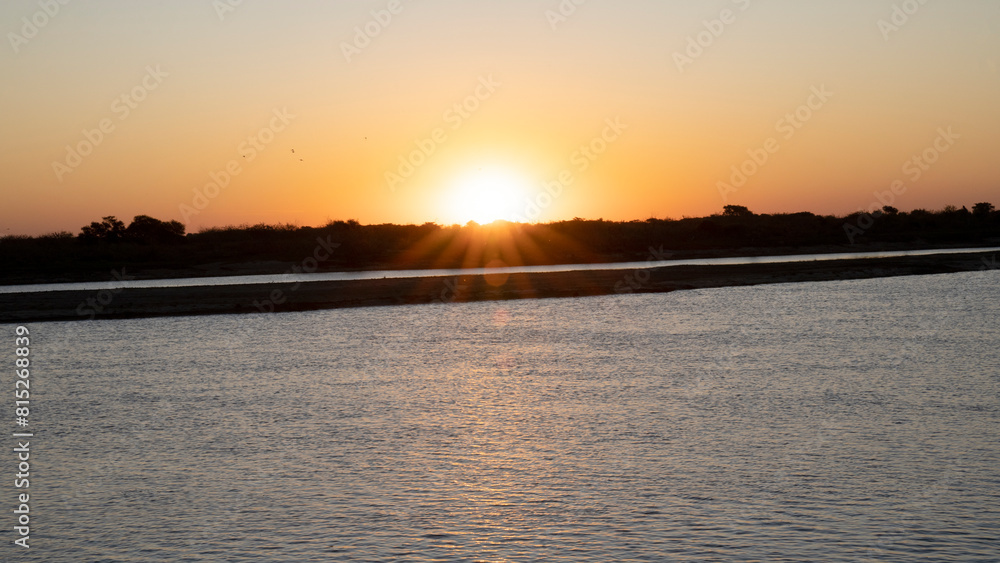 Panorama view of the river at sunset. Beautiful lens flare created by the hiding sun in the horizon. Panorama view of the river at sunset. Beautiful lens flare created by the hiding sun in the horizon.