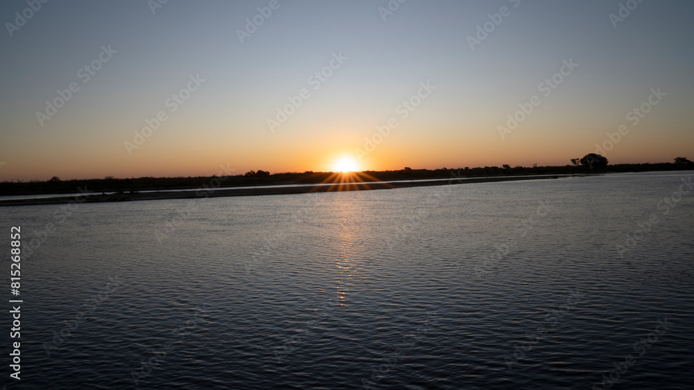 Panorama view of the river at sunset. The sun hides in the horizon. Panorama view of the river at sunset. The sun hides in the horizon.