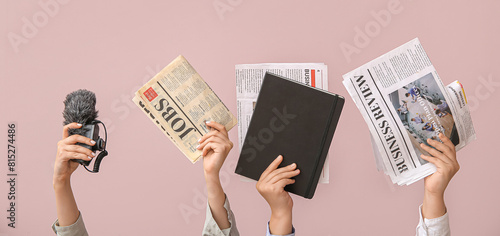 Φωτογραφία Female hands with different newspapers, notebook and microphone on color backgro