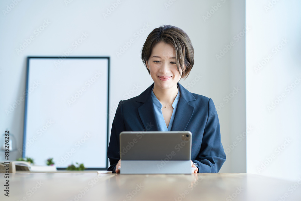 タブレットPCの前に座るスーツ姿の女性