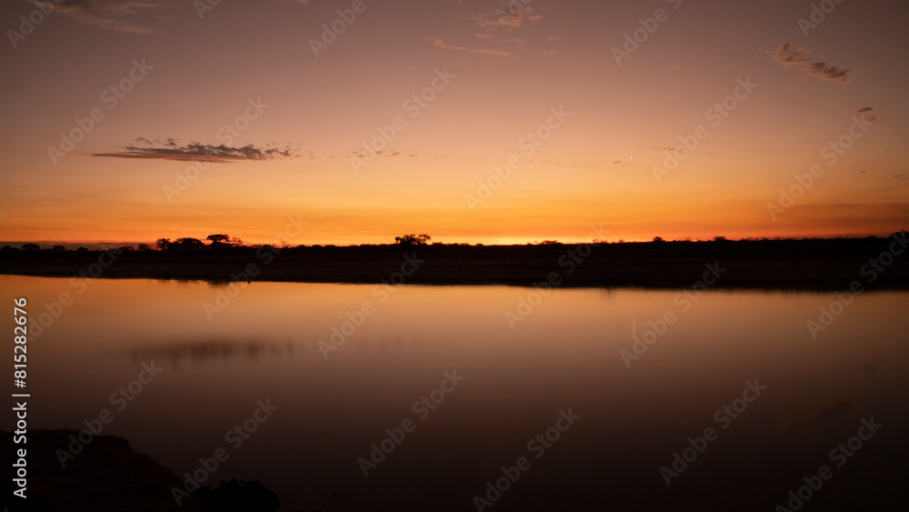 Long exposure shot of the river and coast at nightfall. Beautiful sunset sky reflection in the water surface.	
