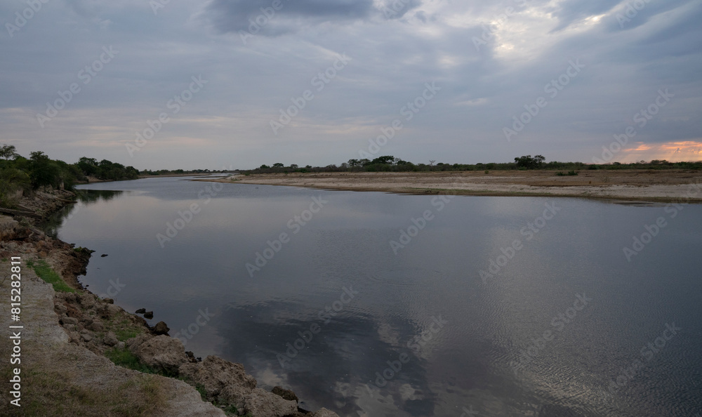 Panorama view of the calm river and shore under a magical sunset sky