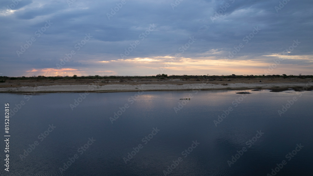 Panorama view of the calm river and shore under a magical nightfall sky
