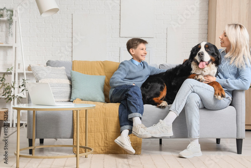 Little boy and his mother with Bernese mountain dog sitting on sofa at home photo