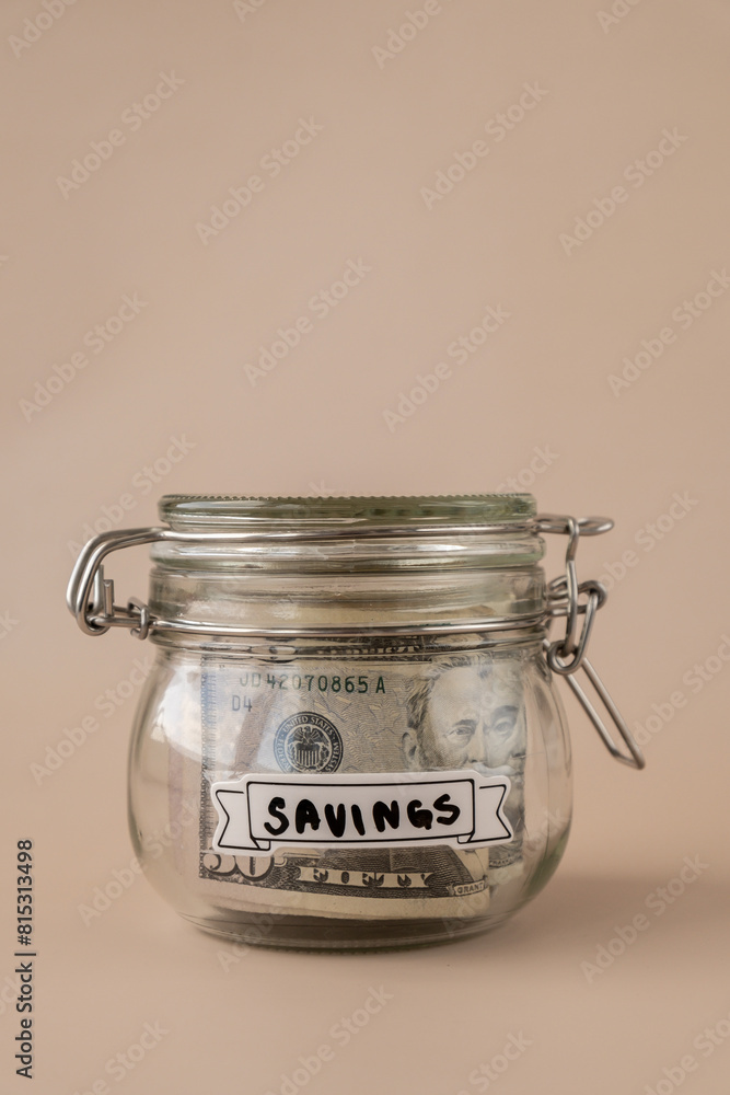 Glass jar full of American currency dollars cash banknote with text SAVINGS. Preparation saving money. Moderate consumption and economy. Collecting money Glass jar full of American currency dollars cash banknote with text SAVINGS. Preparation saving money. Moderate consumption and economy. Collecting money