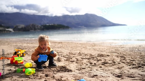 Little girl digs sand with a toy shovel and puts it in a plastic molding on the beach. High quality 4k footage